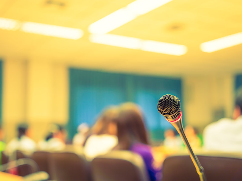an event with people in the background with microphone in foreground