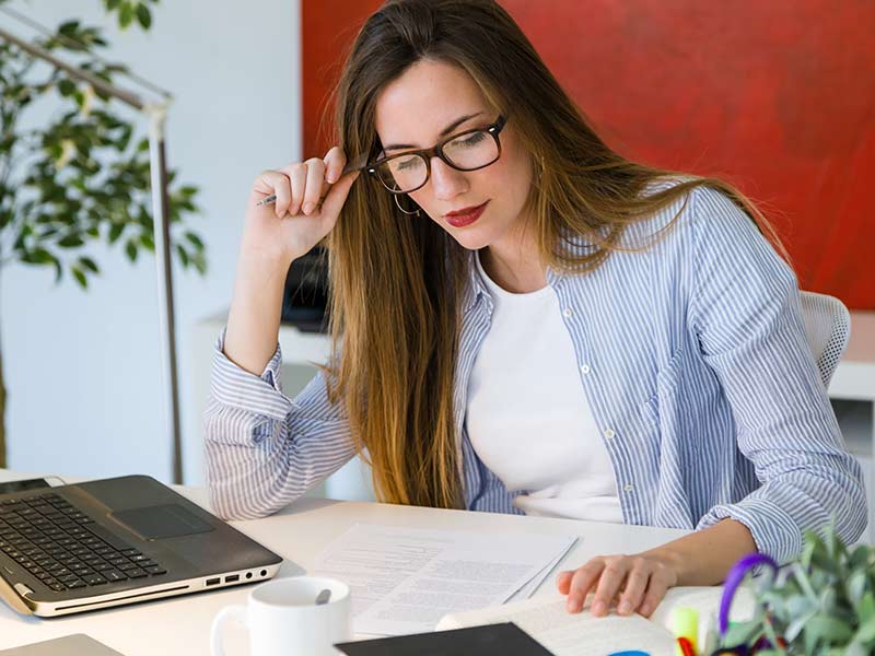 picture of a woman studying with a laptop and documents